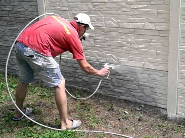 Bir adam bir çit beyaz boya ile boyar.