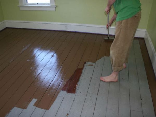 Mujer pinta un piso de madera