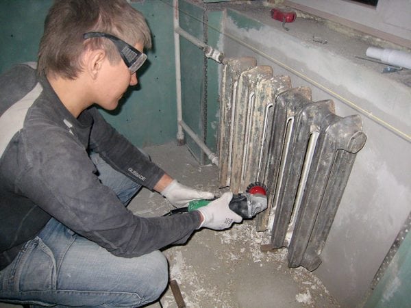 En mand fjerner gammel maling fra metal