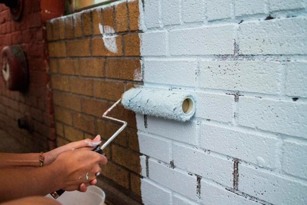 Applying paint to a brick wall