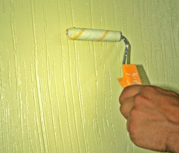 יישום צבע פניני על הקיר באמצעות גלגלת