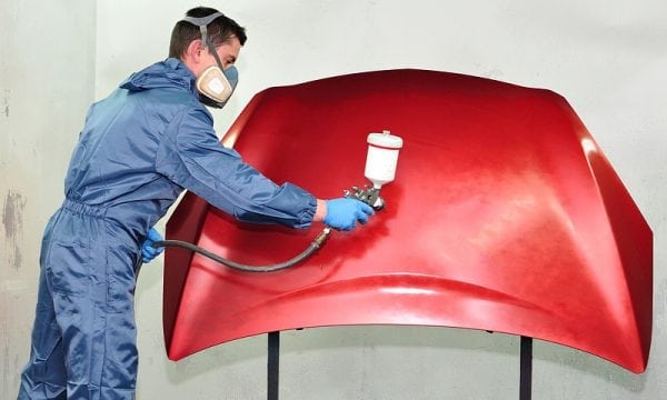 Application of red paint on metal with a spray gun