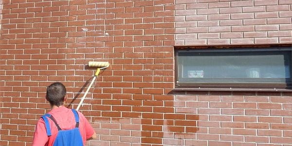 Application of varnish on a brick wall with a roller