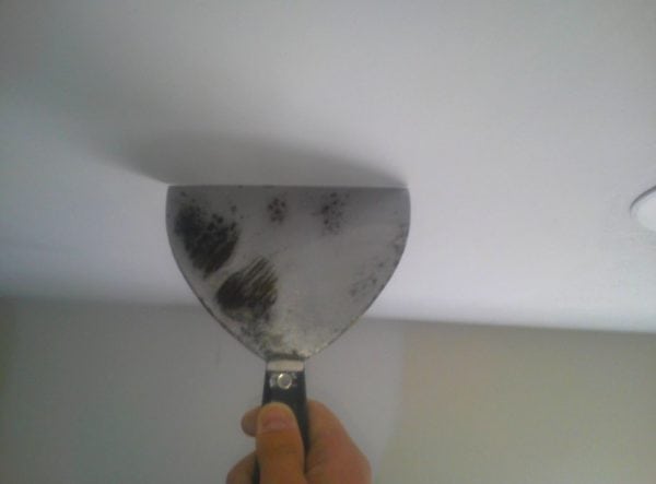 Using a spatula to clean the ceiling