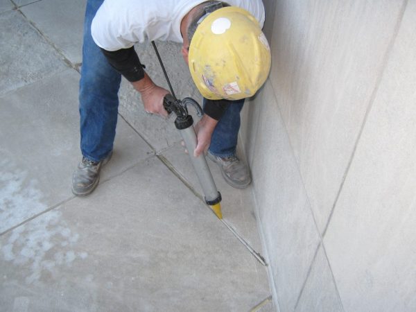 Opvullen van voegen in een betonnen vloer met een bouwspuit