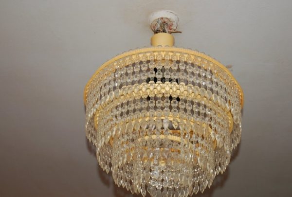 Ang isang dilaw na plastik na chandelier ay nagbibigay sa silid ng isang kahabag-habag na hitsura